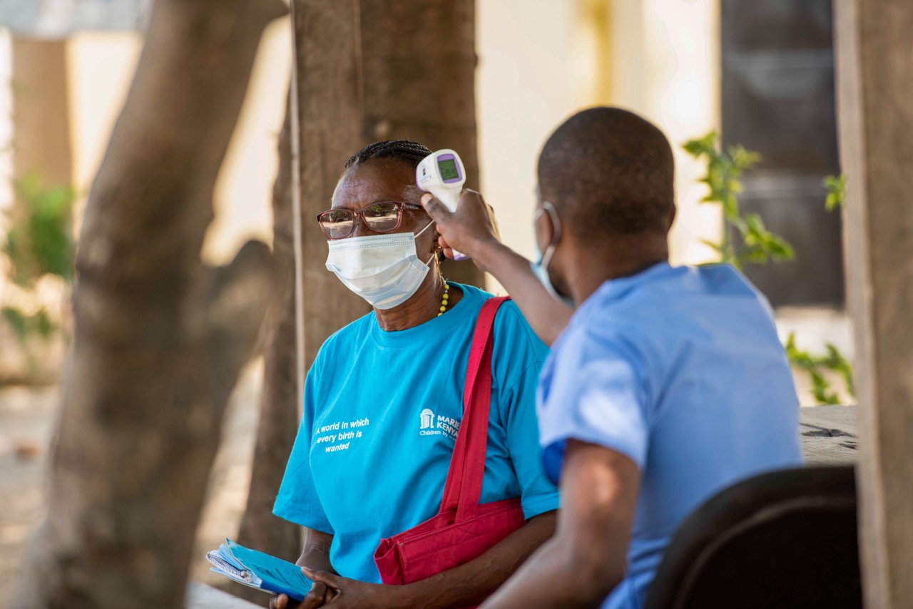 MOMBASA COUNTY: Henry Abungu, head of COVID-19 vaccination at Tudor Subcounty Hospital, takes the temperature of Magoretti Malelu, community health volunteer